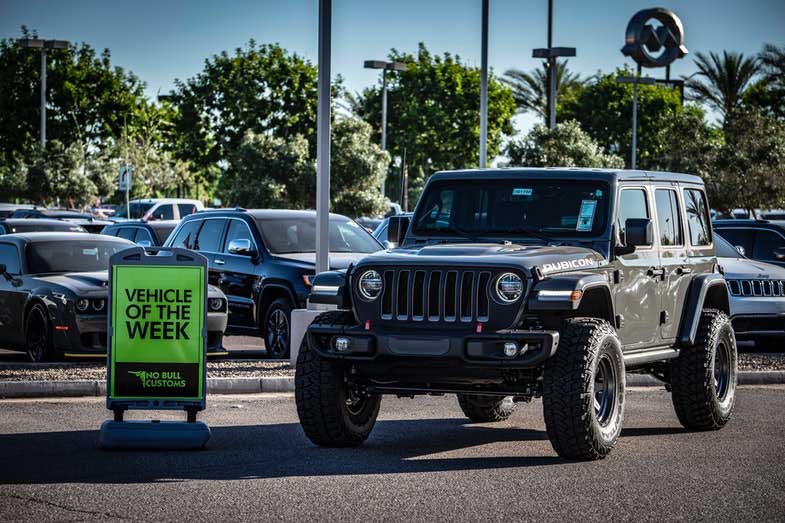 Black Jeep Wrangler Parked Beside a Vehicle of the Week Sign