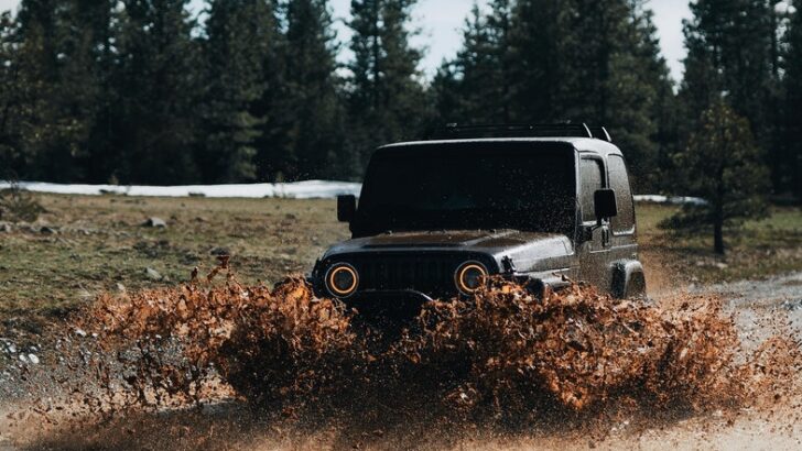Black Off-Road Vehicle Driving Through Mud Puddle