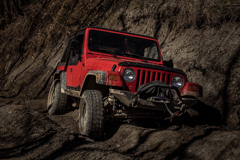 Muddy, Red Jeep Wrangler Off-Roading