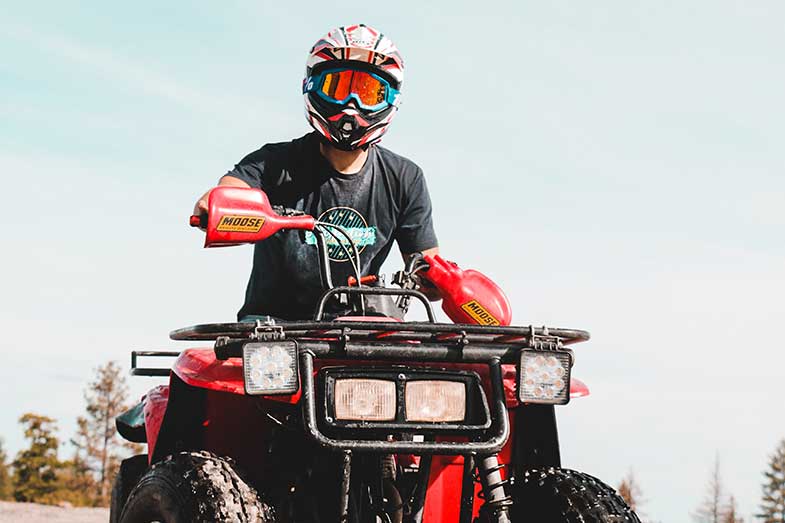 Person with Helmet and Goggles Riding Red ATV