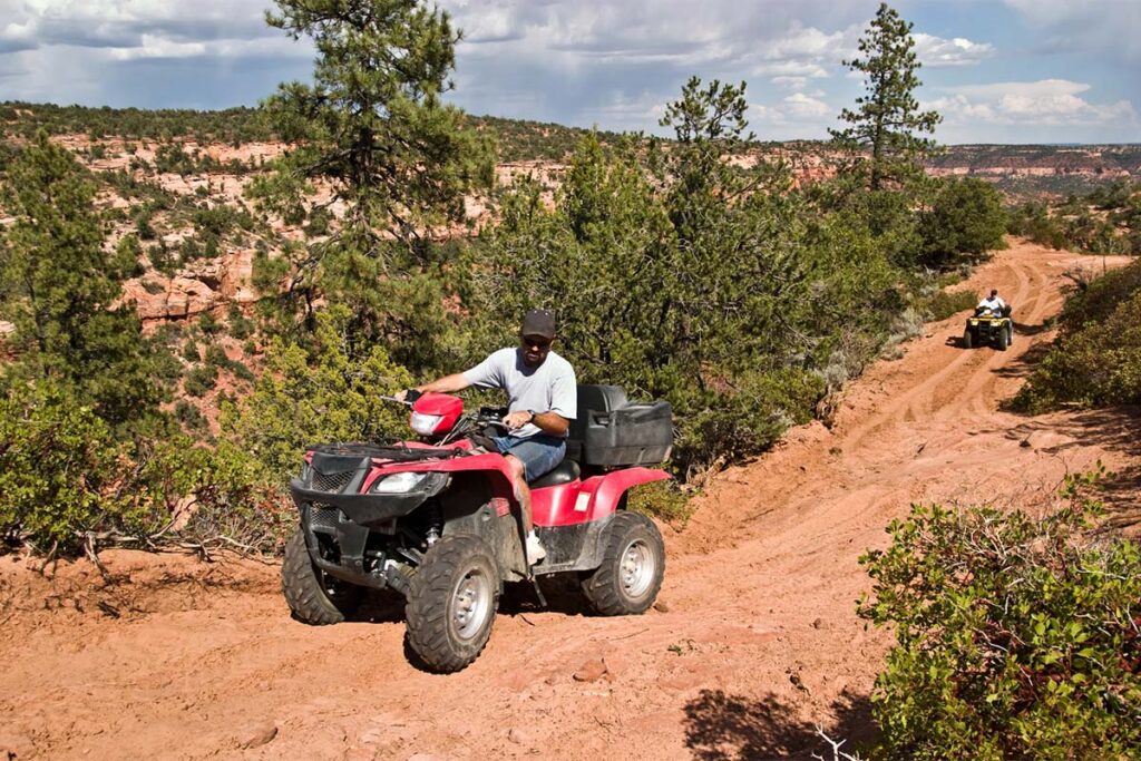 Two People Riding ATVs on Dirt Path