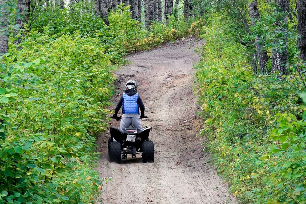 Young Child Quads Up Hill Through Forest