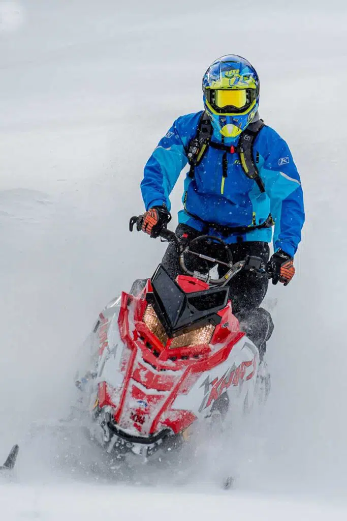 Person in Blue Jacket Riding Red Snowmobile