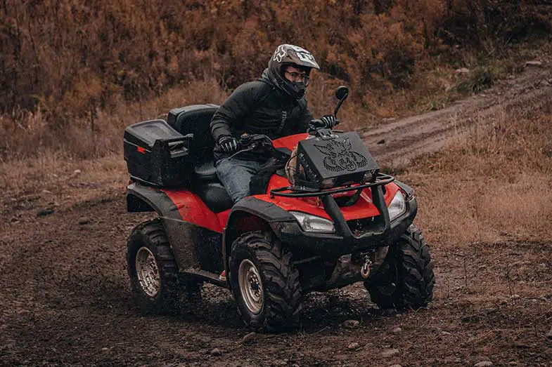 Person Riding a Red ATV on a Muddy Trail