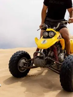Person Riding Yellow ATV on Sand