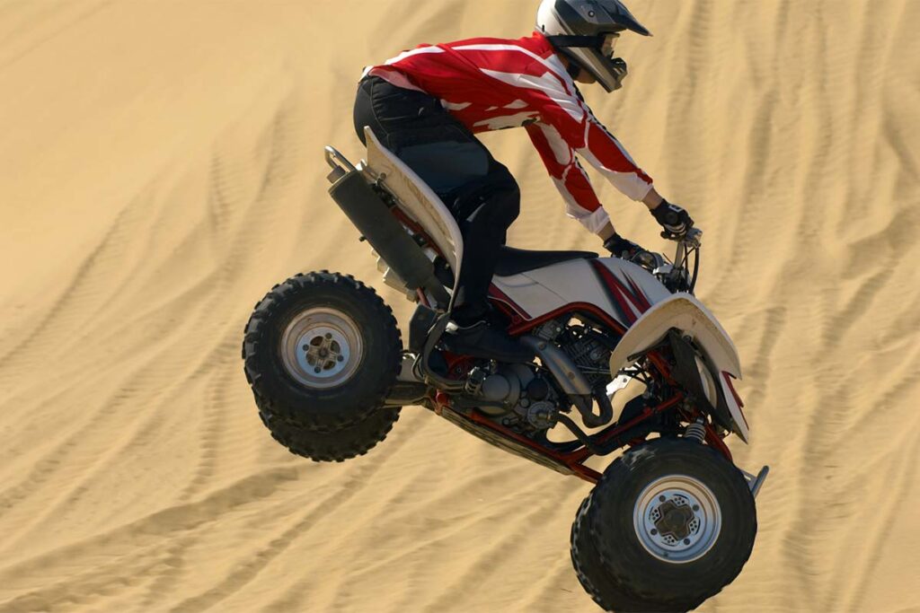 Quad Bike Rider in Mid-Air Jump Over Sand
