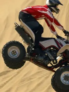 Quad Bike Rider in Mid-Air Jump Over Sand