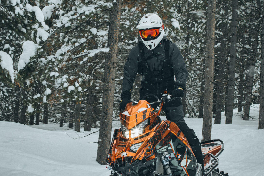 Person Riding Orange Snowmobile