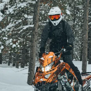 Person Riding Orange Snowmobile