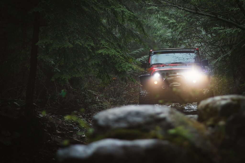 Red Jeep Off-Roading on Rocky Terrain in a Forest