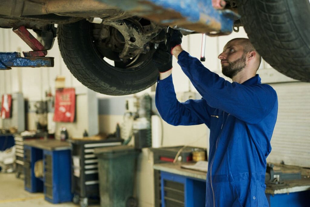 Mechanic in Blue Work Clothes Fixing Car