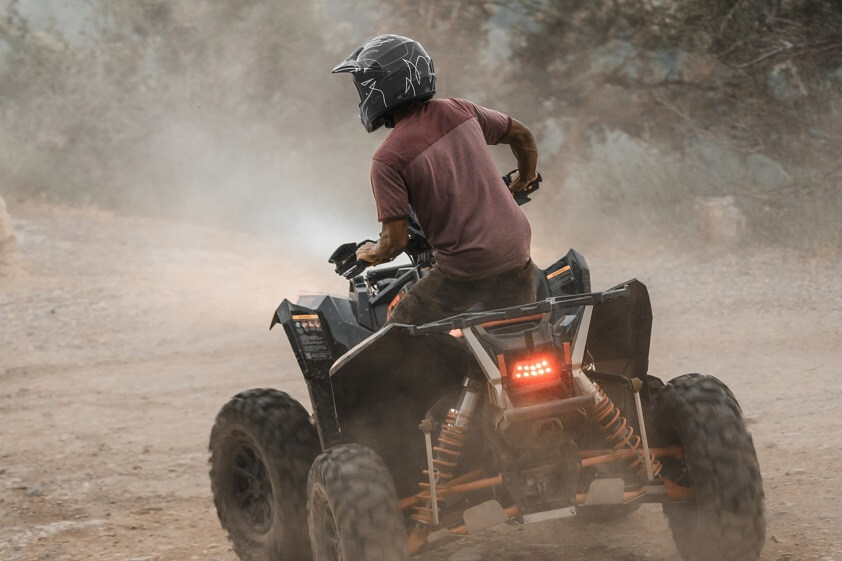 A Man With a Helmet Driving an ATV on a Dirt Road