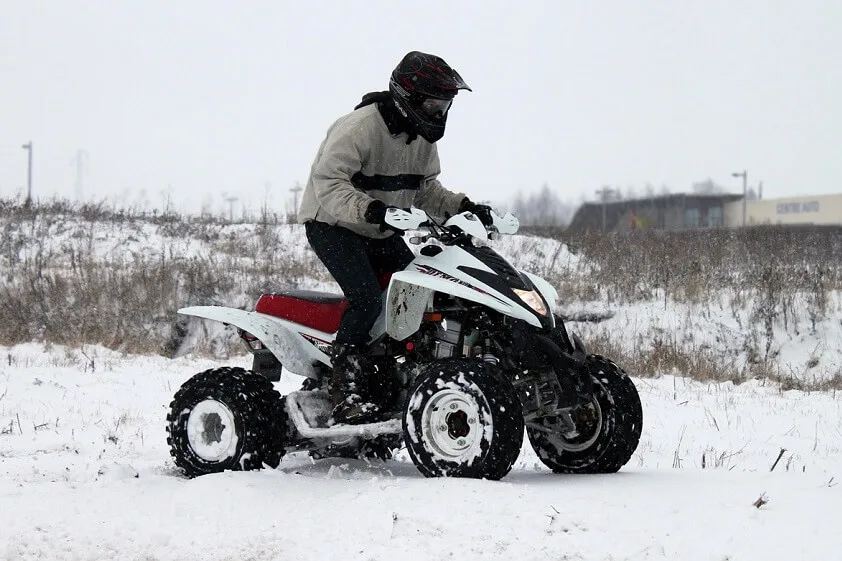 Person Riding a White ATV in the Snow