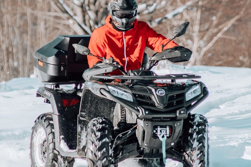 Person Wearing Helmet and Red Jacket Riding ATV