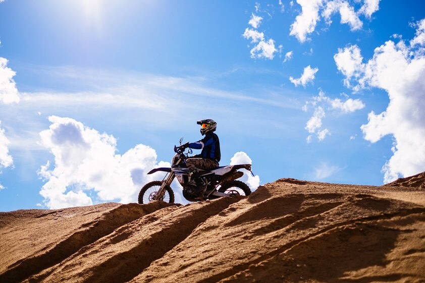Person Riding Motocross Dirt Bike on Sandy Hill