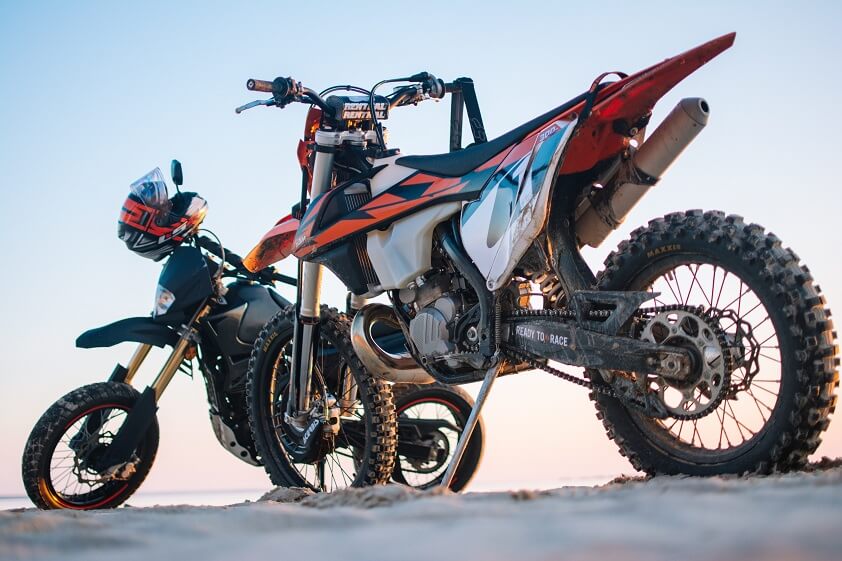 Two Dirt Bikes Parked on Sandy Terrain