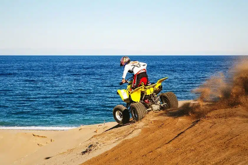 Yellow ATV Riding on Beach Near Ocean