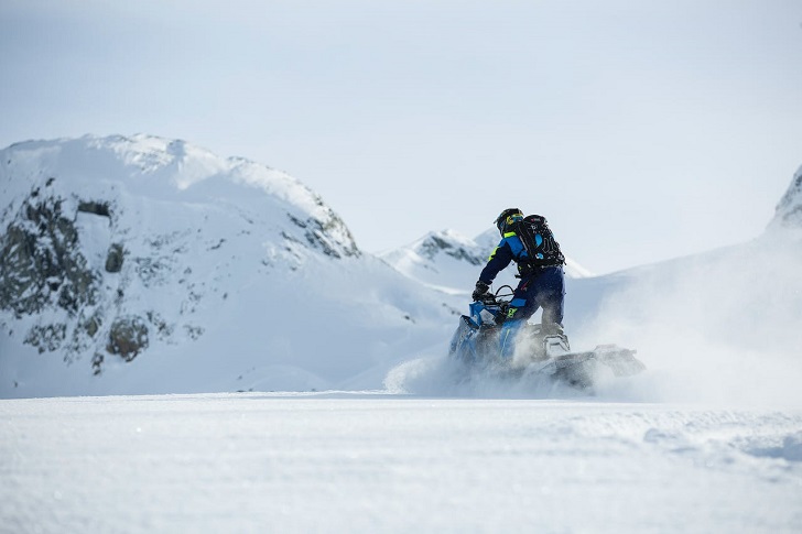 Person in Blue Riding Snowmobile During Winter
