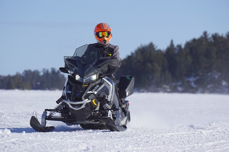 Person With Orange Helmet Riding Black Polaris Snowmobile