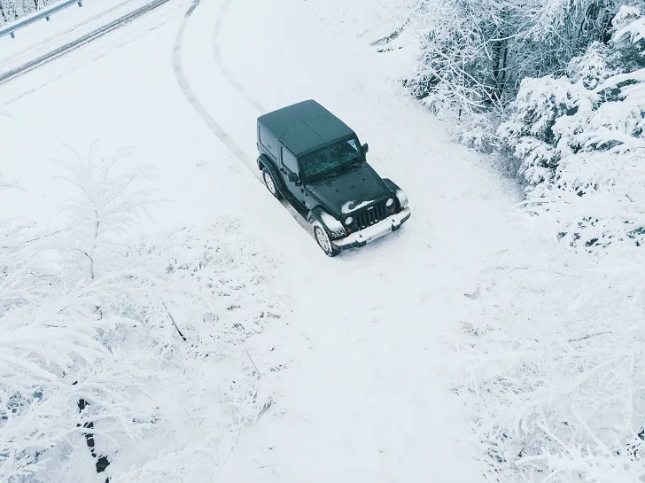 Black Jeep Wrangler Driving Through Winter Snow