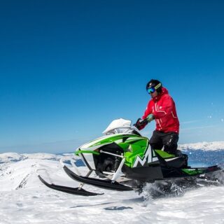 Man in Red Jacket Riding Green Snowmobile